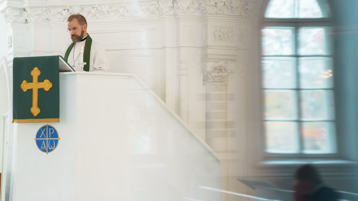 A preacher standing at a pulpit inside a historic church during a religious ceremony.